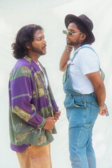 Malaysian Indian men in a group against a cloth backdrop in a park surrounded by trees, talking,...