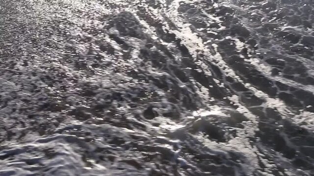 Sunset sunlight reflecting on the wave-wet beach sand