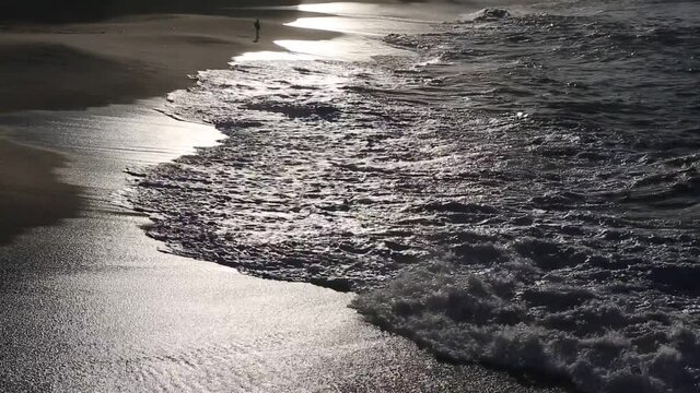 Sunset sunlight reflecting on the wave-wet beach sand