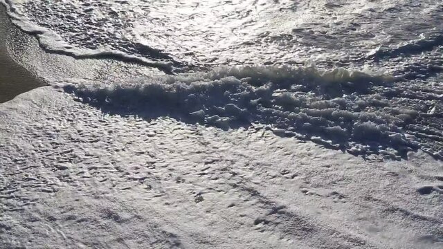 Sunset sunlight reflecting on the wave-wet beach sand