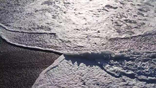 Sunset sunlight reflecting on the wave-wet beach sand