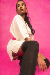 Malaysian Indian individual laughing and posing in a studio setting with a pink background