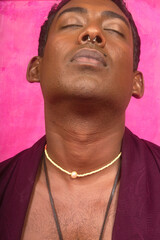 Malaysian Indian individual laughing and posing in a studio setting with a pink background