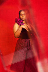 Malaysian Indian individual dressed in red clothing, against a red background, posing and laughing
