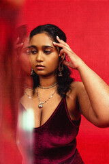 Malaysian Indian individual dressed in red clothing, against a red background, posing and laughing