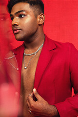 Malaysian Indian individual dressed in red clothing, against a red background, posing and laughing