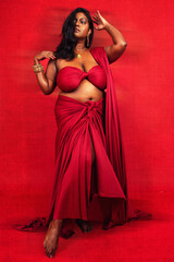 Fototapeta premium Malaysian Indian individual dressed in red clothing, against a red background, posing and laughing