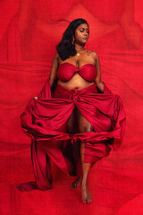 Malaysian Indian individual dressed in red clothing, against a red background, posing and laughing