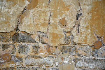 Textured background of an old wall with scuffed plaster and bricks and cracks