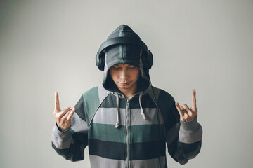 Teenager wearing hoodie and wearing headphones, Rock music gesture.