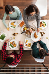 Top view of family Christmas dinner gathering. Mother serve roasted chicken to daughter. Vertical...