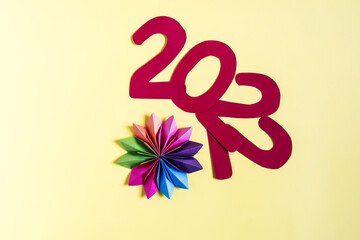 The number of 2022 and a multi-colored paper snowflake on a colored background close-up