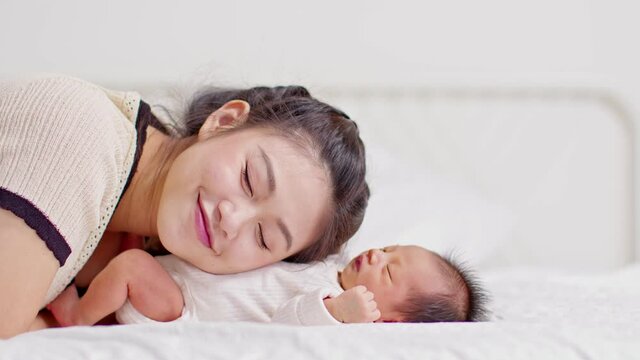 Beautiful Attractive Asian mom  kissing on baby belly sweet and lovely.Happy mother and infant baby looking together smile with love.Mother and baby newborn Concept