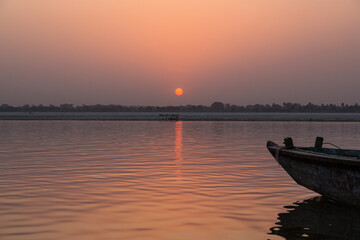 インド　ヴァラナシの早朝のガンジス川に浮かぶボートと朝日でオレンジ色に染まった空