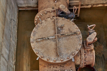 Close-up of an old valve for connecting a water supply pipeline in a concrete bunker on a...