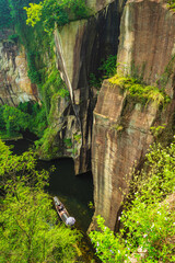 cliff above the smooth lake and small boats. Location: Shaoxing, Zhejiang, China.