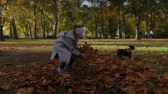 Girl throwing autumn leaves in the park