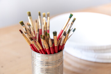 Close-up of red paint brushes in a metal jar.