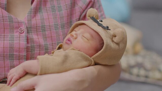 Adorable sleeping newborn baby relax in mother arm safety and comfortable.Smile Asian newborn infant baby resting sleeping sweet dream.Mother holding infant baby.Newborn Baby photography concept