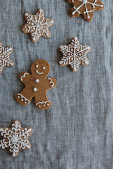 Christmas gingerbread man and snowflakes cookies on neutral linen cloth background. Flat lay, top view