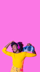 Young black woman dancing listening music holding boombox wireless headphones feeling free smiling happy isolated advertising copyspace