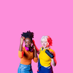 Young diverse black and caucasian women wireless bluetooth speaker dancing together having fun laughing isolated advertising background