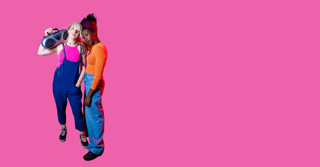 Two young diverse women holding boombox posing confident isolated copyspace advertising background