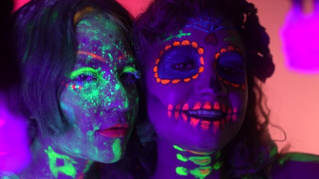 Neon Halloween make up for Day of the Dead celebration in Mexico. Ultra violet neon portrait photography with two hispanic girls. 
