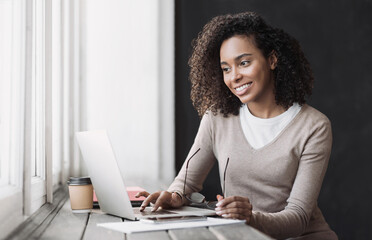 Young woman using laptop computer at office. Student girl working at home. Work or study from home, freelance, business, lifestyle concept.