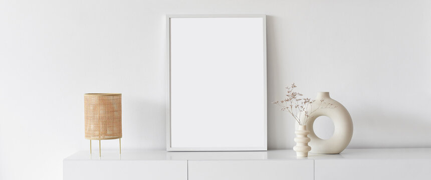 Blank picture frame mockup on white wall panoramic banner. White living room design. View of modern scandinavian style interior. Home staging and minimalism concept.