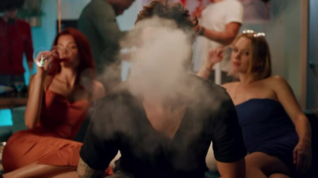 Man smoking hookah near girlfriends