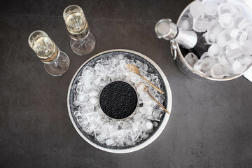 Black caviar in can on ice, champagne in glass and bottle in a bucket