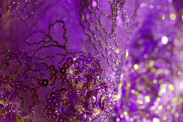 Purple gold bokeh effect. Intricate embroidery of beads and sequins on transparent drape.