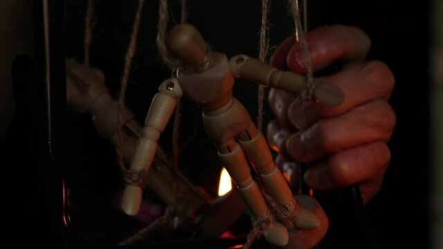 a wooden man on ropes tied to a man's hand, manipulation of people and slavery, free will, power