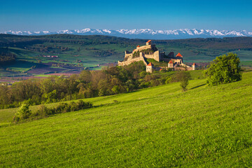 Rupea fortress and green fields with snowy mountains in background