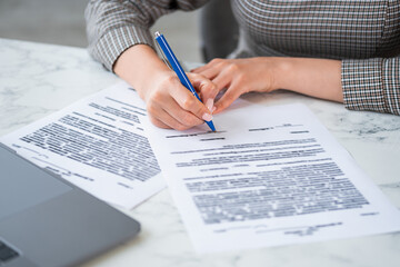 Businesswoman hands signing the legal contract, papers and pen, closeup, documents with computer on working desk. Concept of business agreement and deal