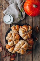 Pumpkin buns bread with cinnamon on retro tray over rustic wooden background. Autumn, Halloween food concept.