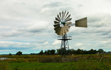 Old metal windmill powers a pump to regulate the water level in a dutch ditch.