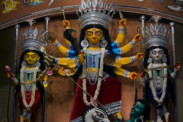 Goddess Durga idol at decorated Durga Puja pandal, shot at colored light, in Kolkata, West Bengal,...