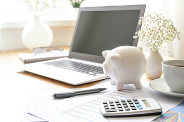Finance accounting on a desk with laptop computer, calculator, piggy bank, and documents, business...