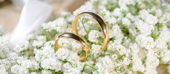 wedding rings lie on a beautiful bouquet white as bridal accessories - wedding rings stand on white...