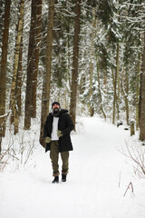 Fototapeta na wymiar Bearded man in the winter woods. Attractive happy young man with beard walk in the park.