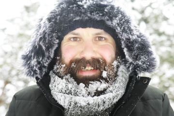 Bearded man in the winter woods. Attractive happy young man with beard walk in the park.