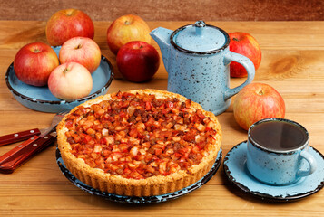 Homemade pie with apples, raisins and cinnamon on wooden table.