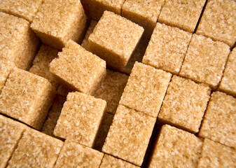 Refined sugar cubes on white background. Brown sugar cubes in background
