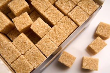 Refined sugar cubes on white background. Brown sugar cubes in background
