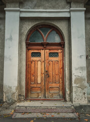 Vintage wooden door and weathered facade details of an old historical building. Outdoors architecture elements. Rustic doorway