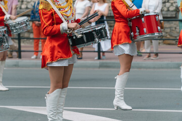 Street performance of festive march of drummers girls in red costumes on city street. Young girls...