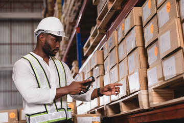 Naklejka na ściany i meble Black male staff using digital barcode scanner working checking stock in logistic warehouse