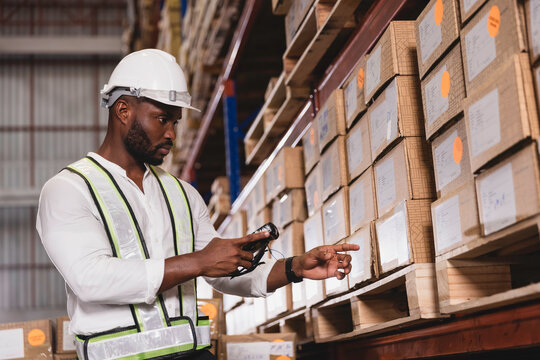 Black male staff using digital barcode scanner working checking stock in logistic warehouse
